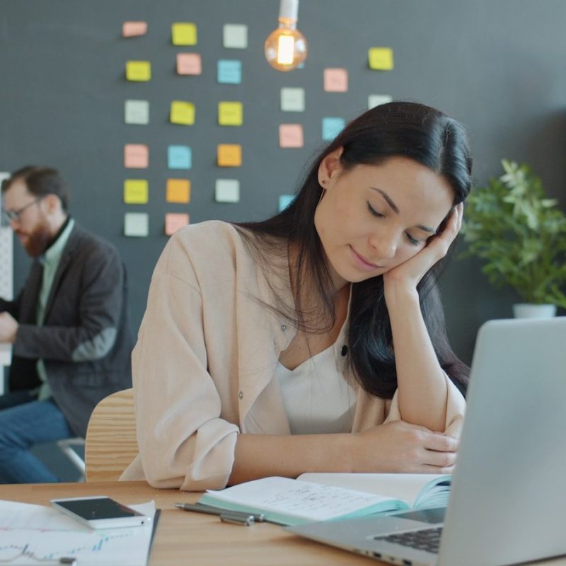 Woman resting head on hand at desk