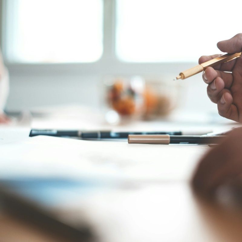 shallow focus photo of person wearing ballpoint pen