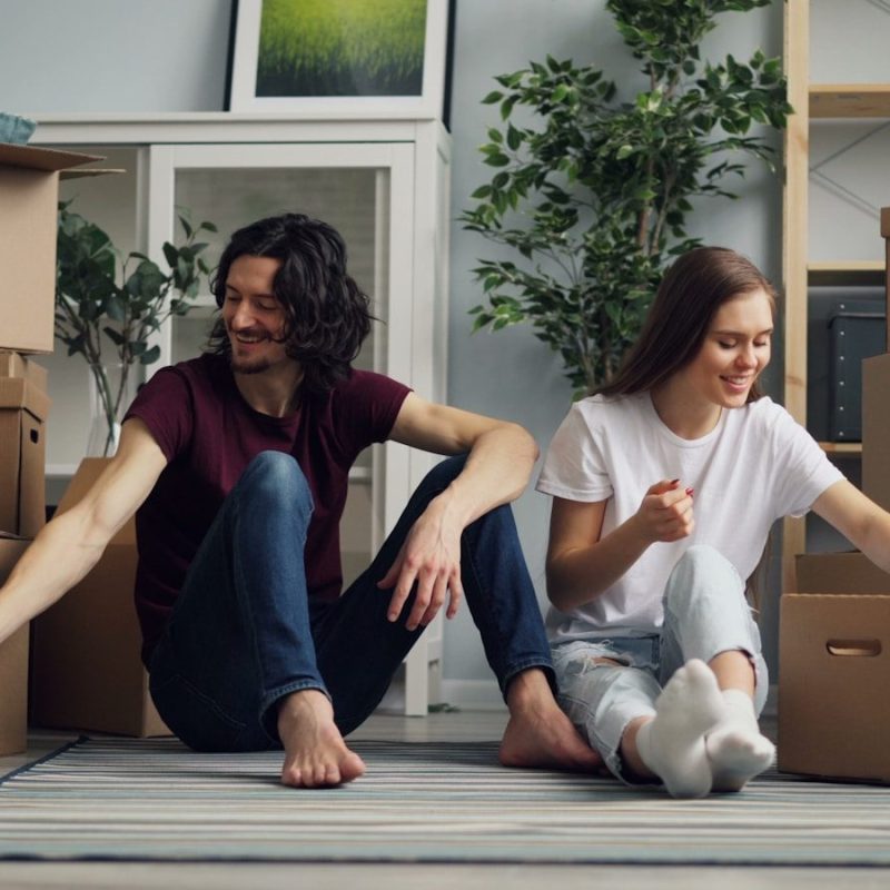 a man and a woman sitting on the floor surrounded by boxes